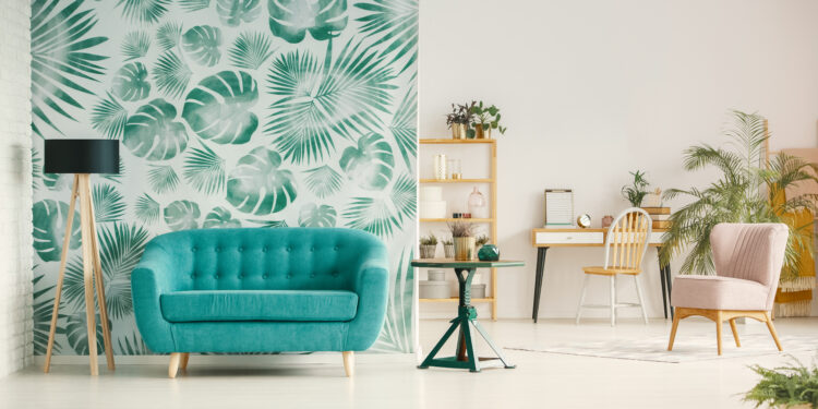 Blue couch between lamp and table in open space interior with green wallpaper and chair. Real photo